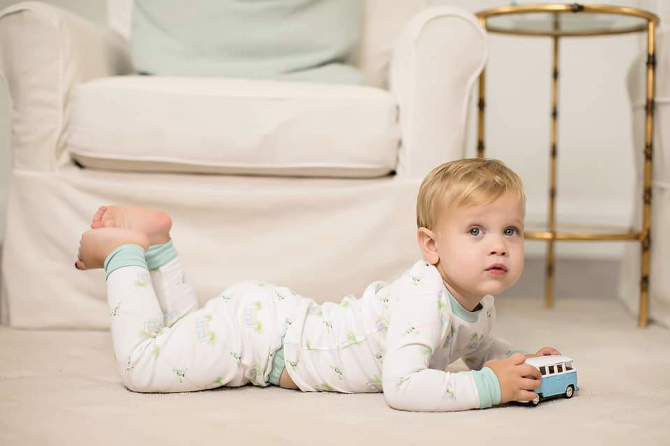 Little boy in Hadley's pajama set laying on his stomach holding toy truck